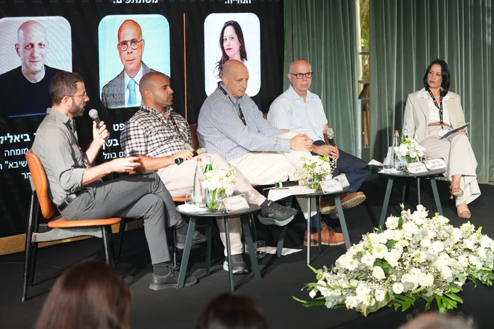 Five participants in a panel discussion on the conference stage